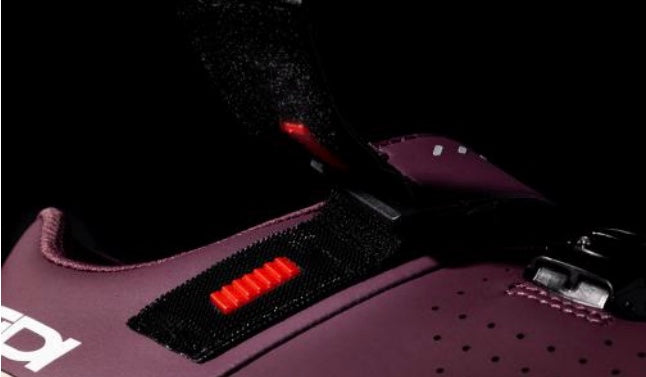 Close-up of a purple seat belt with a red buckle and black velcro strap on a dark background