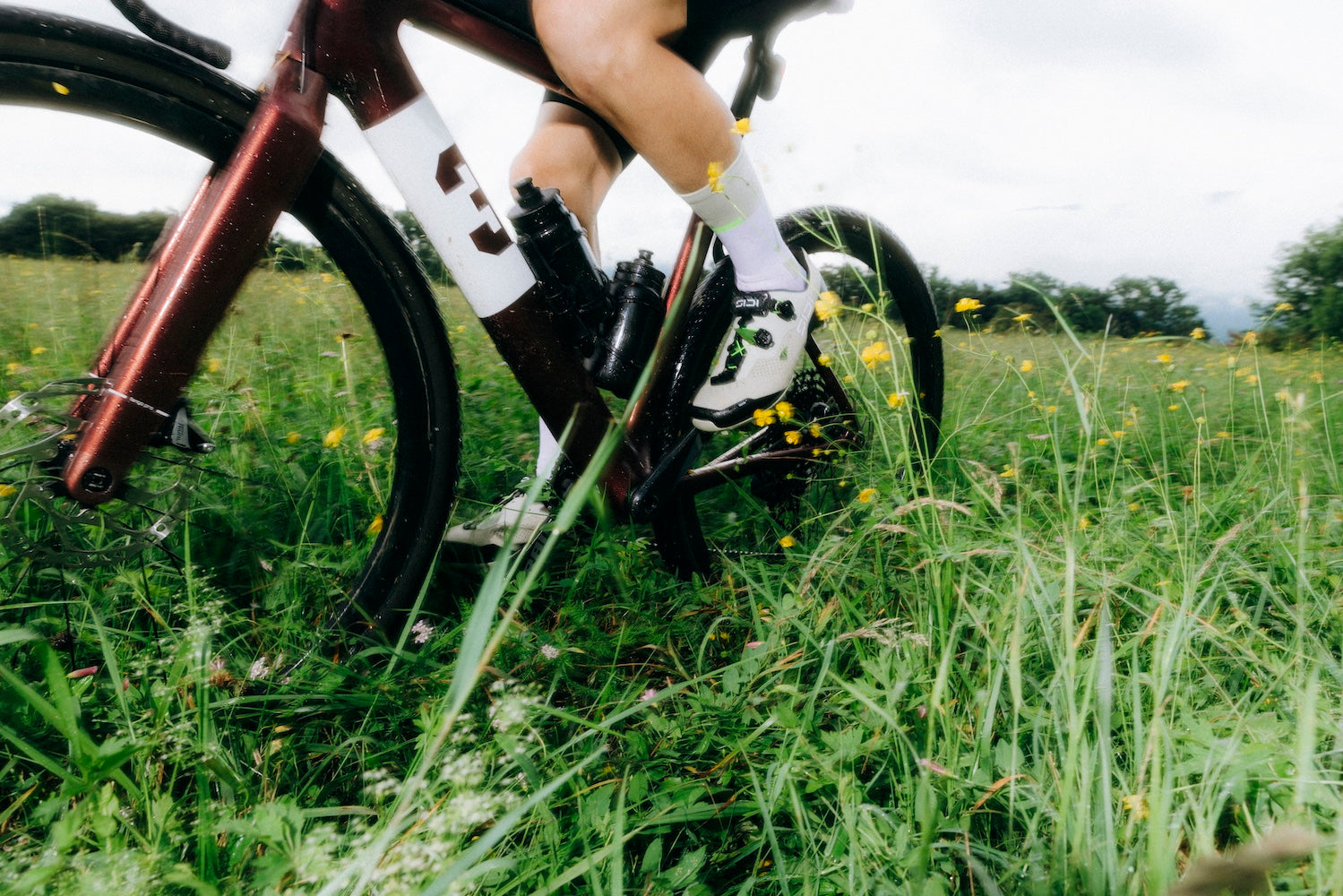 Cyclist rides through grassy field while wearing SIDI Dominator X shoes.