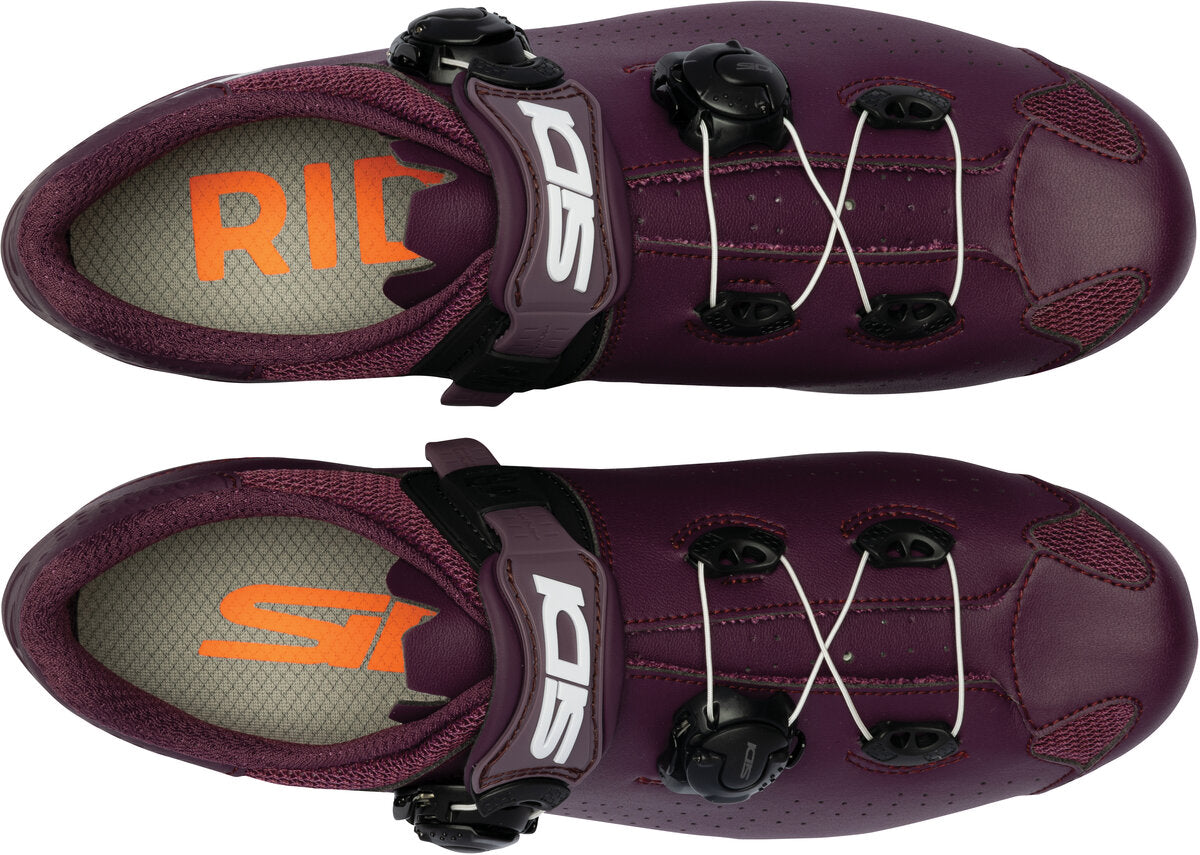 Pair of purple cycling shoes with orange and white branding on a white background