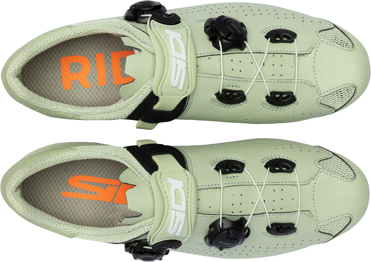 Pair of light green cycling shoes with orange and white branding on a white background